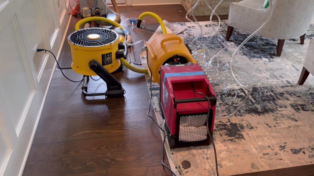 Air movers drying a hardwood floor mid-demolition