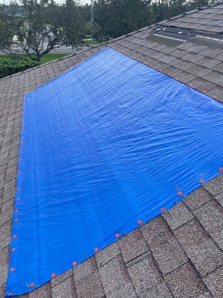 Emergency tarp secured over a storm-damaged roof